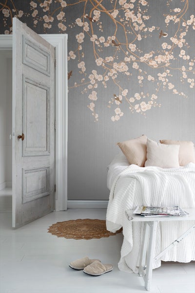 Helles Schlafzimmer mit floraler Tapete, Bett und offener Tür