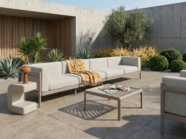 Moderne Gartenlounge mit vierteiligem Sofa, Couchtisch und Beistelltisch auf einer Terrasse aus Betonplatten mit Pflanzen.