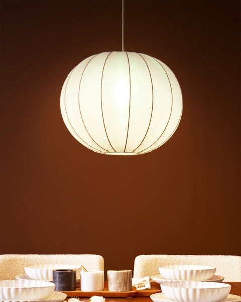 Eine Kugel Pendelleuchte hängt über einem gedeckten Tisch.