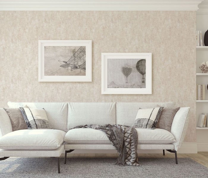 Wohnzimmer mit Sofa, Kissen, Decke, Bildern und Regal.