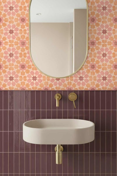 Modernes Badezimmer mit orientalisch gemusterten Wandfliesen, dunkelroten vertikalen Fliesen, ovalem Waschbecken und goldenen Armaturen.