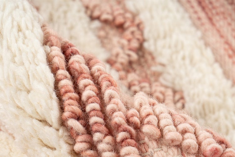 Nahaufnahme eines strukturierten Webteppichs mit dickem Schlingenflor und vertikalem Streifenmuster.