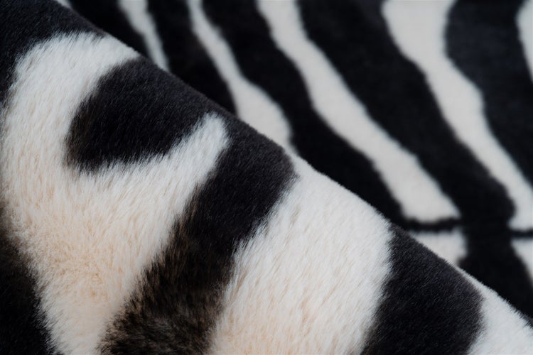 Nahaufnahme eines weichen Kunstfellteppichs mit Zebramuster.