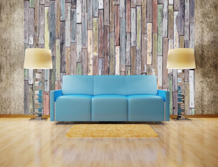 Wohnzimmer mit blauem Sofa, Stehlampen aus Büchern und Holzwand