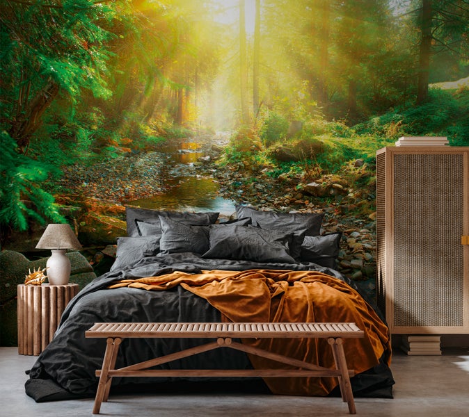 Schlafzimmer mit Fototapete, die einen sonnendurchfluteten Wald mit Bachlauf darstellt.