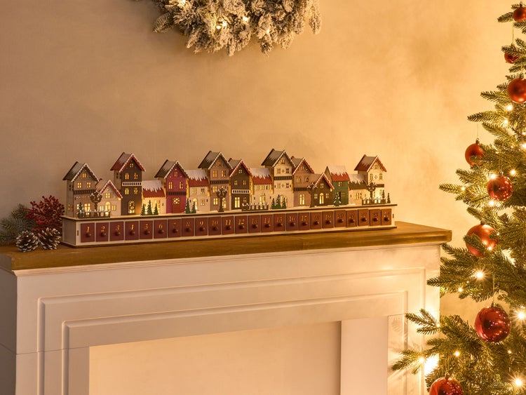 Holz Adventskalender in Form einer Häuserzeile auf einem Kaminsims mit Weihnachtsbaum und Dekoration