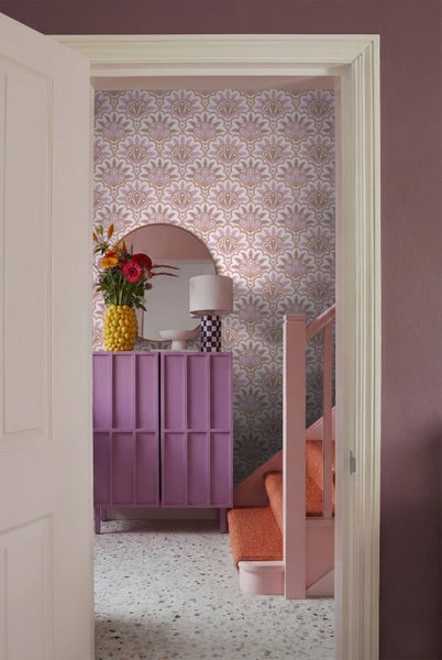 Fluransicht durch eine offene Tür mit Kommode, Spiegel und gemusterter Tapete