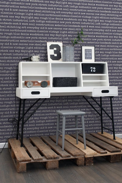 Schreibtisch mit Regalen und einem grauen Hocker auf einer Holzpalette.