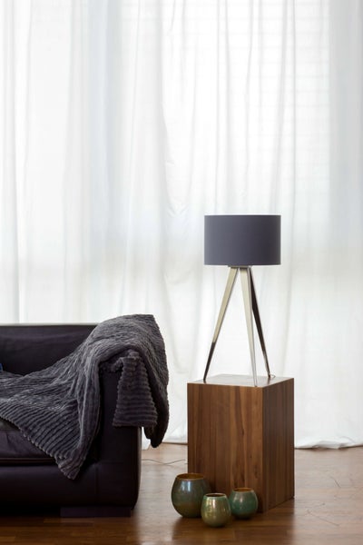 Wohnzimmer mit Sofa, Tagesdecke, Stehleuchte, Holzwürfel und Dekoration