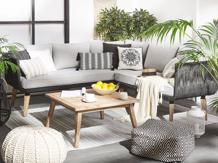 Gemütliche Sitzecke im Freien mit Lounge-Sofa, Holztisch und dekorativen Kissen