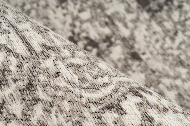 Nahaufnahme eines strukturierten Teppichs mit grau-weißem Vintage-Muster.