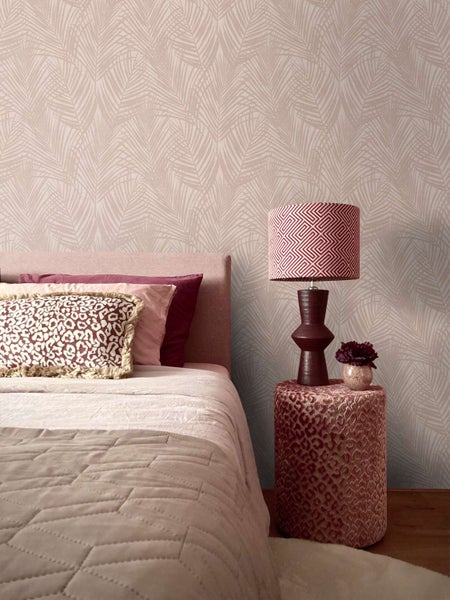 Schlafzimmer mit Blättermustertapete, gepolstertem Bett, gemustertem Nachttisch und Tischleuchte in moderner, gemütlicher Wohnatmosphäre