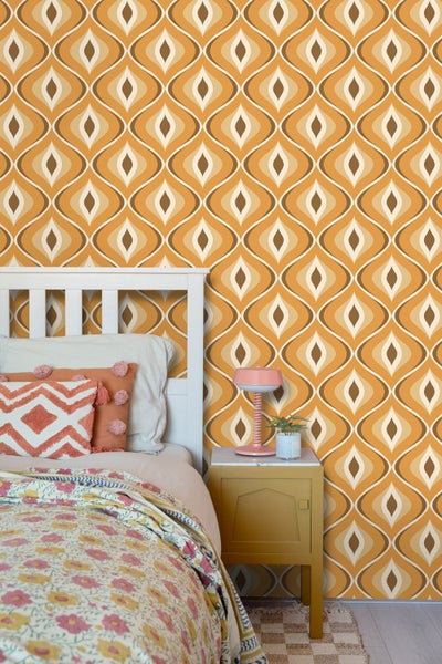 Tapete mit retro-geometrischem Muster in einem hellen Schlafzimmer mit Bett und Beistelltisch.