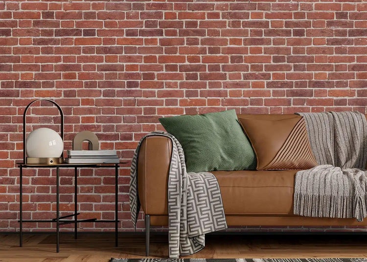 Wandgestaltung mit Tapete in Backstein-Optik hinter einem Ledersofa im industriellen Stil mit Beistelltisch und Lampe.