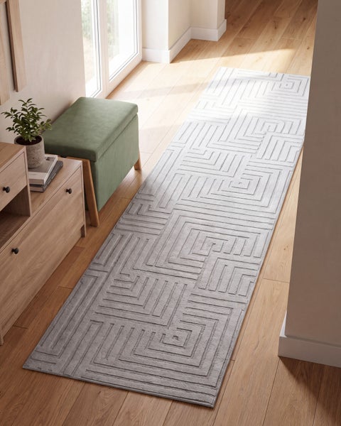 Flur mit Holzboden, einer Sitzbank und einem langen Teppich mit geometrischem Labyrinthmuster in moderner Inneneinrichtung.