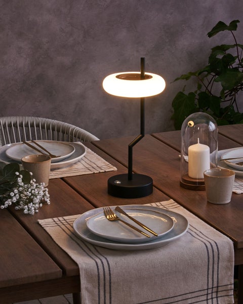 Innenansicht eines Gartenhauses aus hellem Holz mit Essbereich, Sideboard und separatem Abstellraum mit Regalsystem.