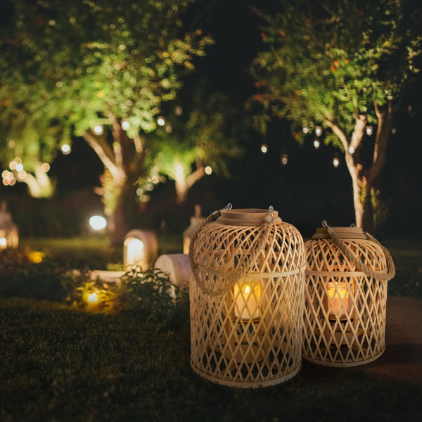 Zwei dekorative Bambuslaternen beleuchten einen Garten bei Nacht.