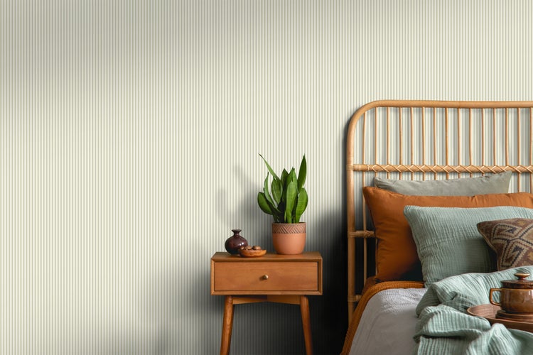 Schlafzimmer mit gestreifter Tapete, Rattankopfteil und Nachttisch