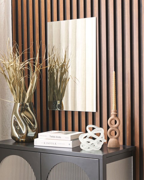 Dekoratives Wohnambiente mit Kommode, Spiegel, Vase mit Trockenblumen, Kerzenhalter und Dekorationselementen