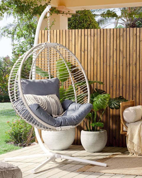 Szene mit einem Schwebesessel aus Rattan mit Kissen auf einer Terrasse