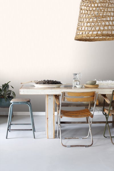 Esszimmer mit Holztisch, Stühlen, Hocker und Rattanhängelampe