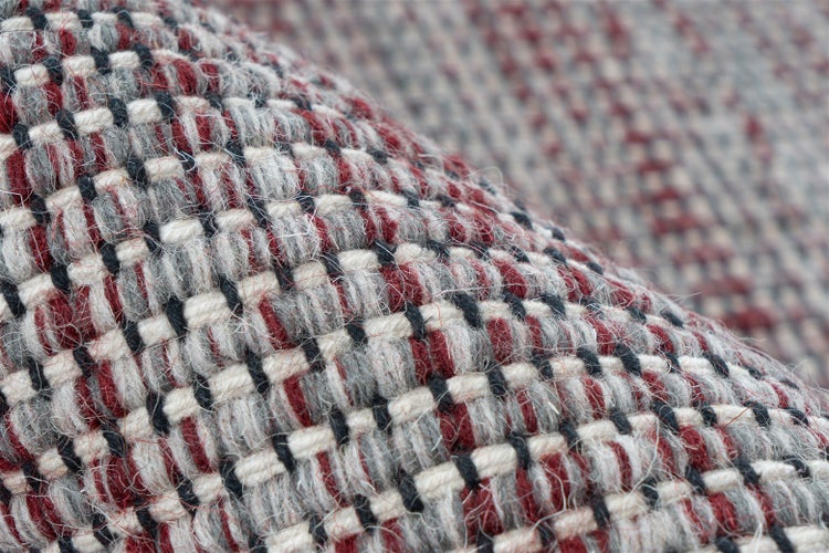 Nahaufnahme eines grob gewebten Teppichs mit Karo-Muster aus roten, schwarzen, weißen und grauen Garnen.