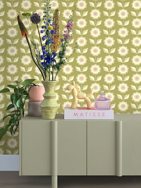 Dekoratives Sideboard mit Blumenmustertapete, Vasen, Topfpflanze und dekorativen Accessoires