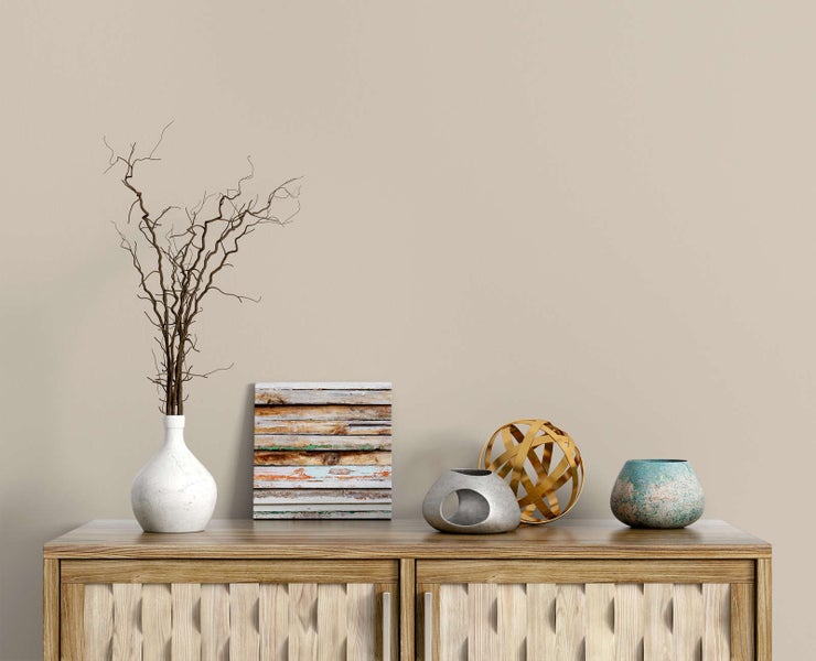 Wohndekoration auf einem hölzernen Sideboard mit weißer Vase, Zweigen, Leinwandbild in Holzoptik, Skulpturen und einer türkisfarbenen Vase.