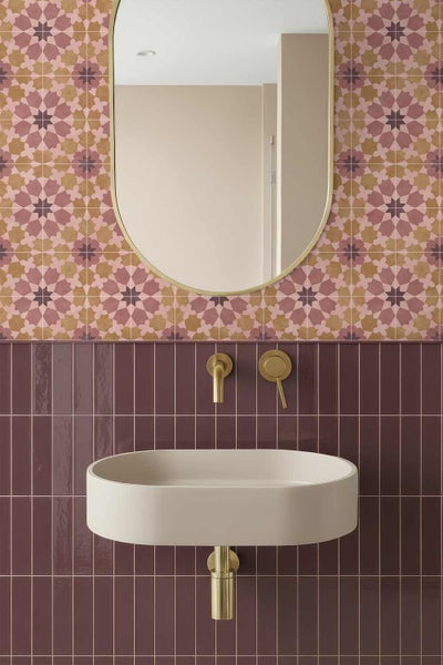 Modernes Badezimmer mit ovalem Waschbecken, goldenen Wandarmaturen, einem ovalen Spiegel und Wandfliesen mit geometrischem Muster.