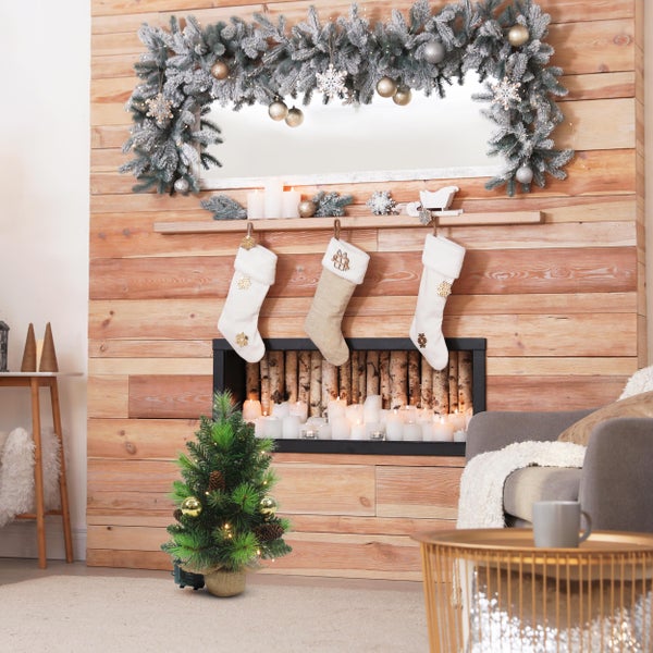 Weihnachtliche Wohnzimmerdekoration mit Kamin, Strümpfen und kleinem Weihnachtsbaum.