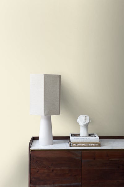 Wandgestaltung mit Lampe, Büchern und Dekoration auf einem Holzschrank.