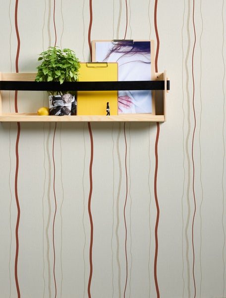 Schlafzimmer mit Bett, Nachttischlampe und Dekoration auf einem Holztisch vor einer gestreiften Tapete