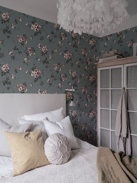 Schlafzimmer mit Bett, Nachttisch und floraler Tapete für eine gemütliche Atmosphäre