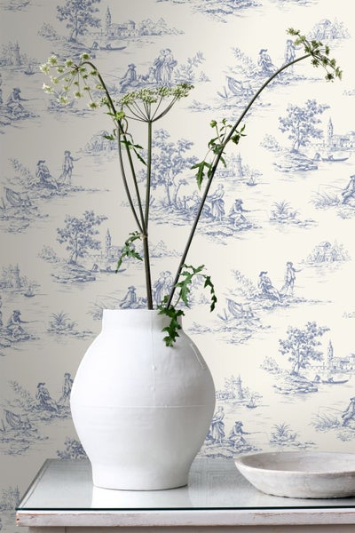 Toile-de-Jouy-Tapete mit blauen ländlichen Szenen, davor eine weiße Vase mit grünen Zweigen und eine Schale.