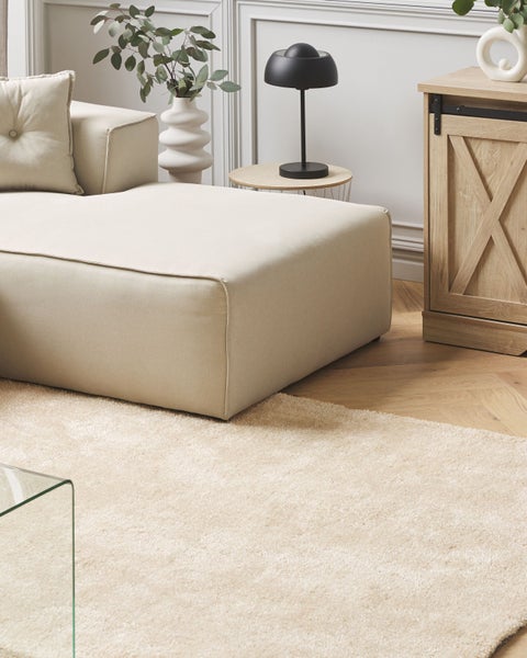 Beige Teppich in einer Wohnzimmerszene mit Sofa und Möbeln