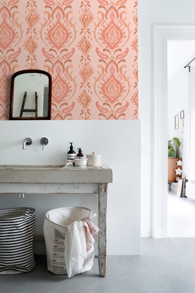 Badezimmer mit Waschbecken, Spiegel und gemusterter Tapete für eine helle und organisierte Atmosphäre.