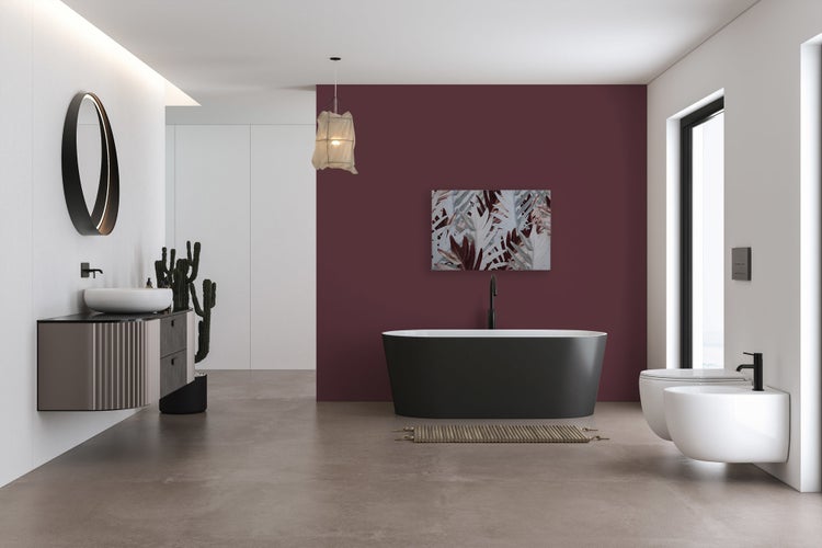 Modernes Badezimmer mit freistehender Badewanne, wandhängendem Waschtisch, wandhängendem WC und Bidet vor einer dunklen Akzentwand.