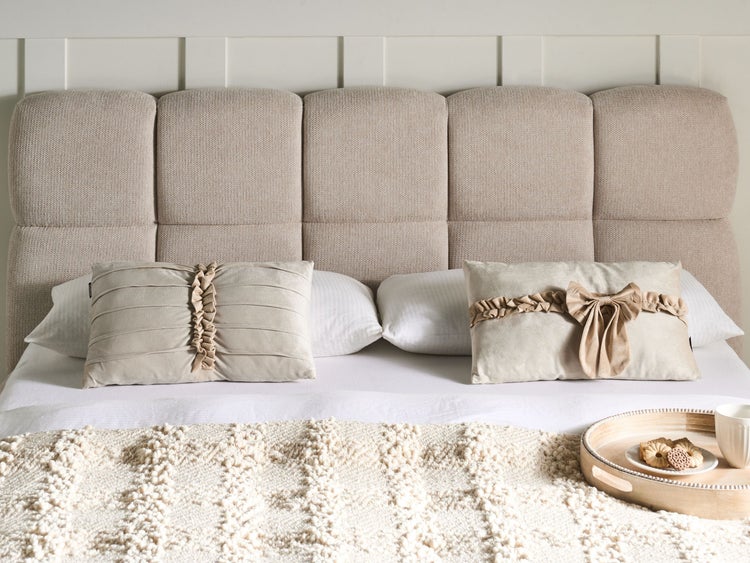 Szene eines Schlafzimmers mit Bett, gepolstertem Kopfteil und dekorativen Kissen