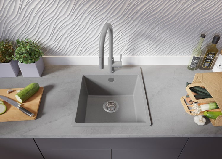 Küchenszene mit Spüle, Armatur, Schneidebrett mit Gemüse und Einkaufstüte