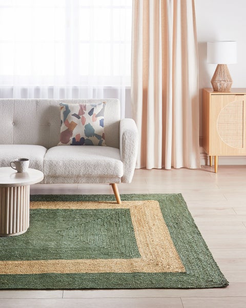Wohnzimmer-Szene mit Sofa, Tisch, Teppich und Kommode für ein helles und organisiertes Ambiente.