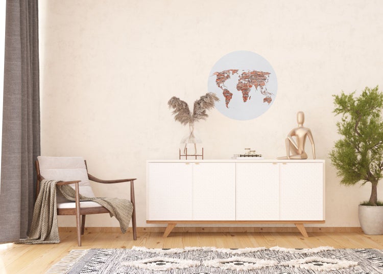 Wohnzimmer mit Sessel, Kommode, Zimmerpflanze und Weltkarte an der Wand