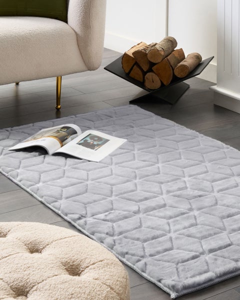 Dekoratives Wohnzimmer mit gemustertem Teppich und Kaminholz