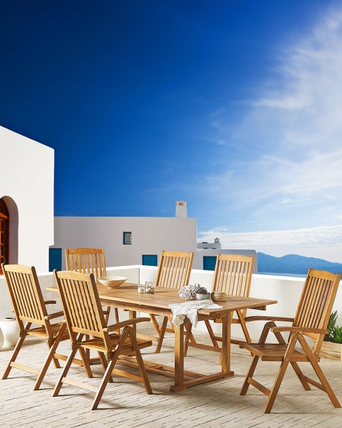 Gartengarnitur aus Holz mit sechs Stühlen und einem Tisch auf einer Terrasse vor einem weißen Gebäude