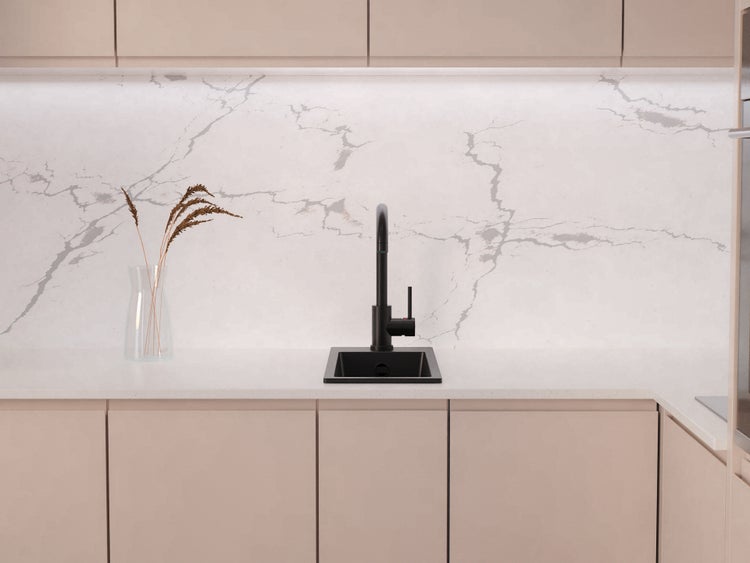 Moderne Küche mit schwarzer Einbauspüle und schwarzer Küchenarmatur vor einer Wand in Marmoroptik.