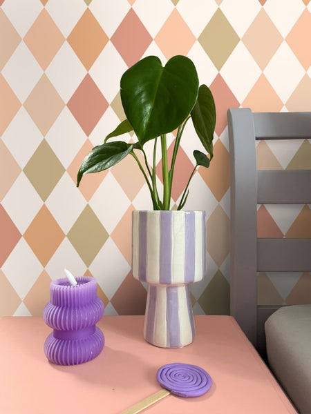 Dekorative Szene mit Zimmerpflanze, Kerze und Kunsthandwerk auf einem Nachttisch