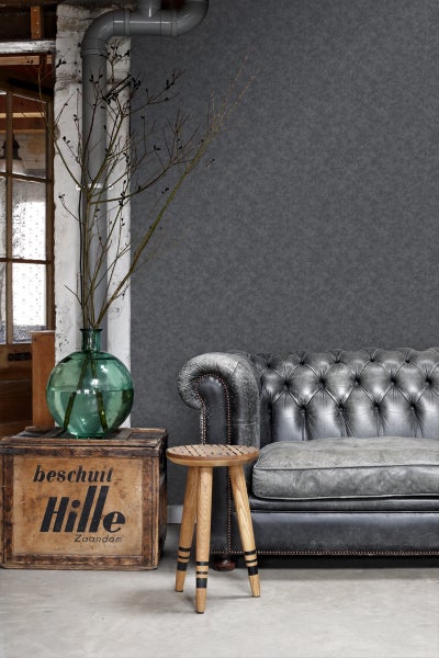 Wohnzimmer mit grauer Tapete, Ledersofa und Holzhocker