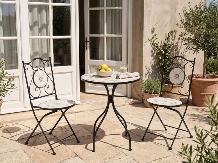 Bistro-Set aus Metall mit Mosaik-Verzierung auf einer hellen Terrasse, runder Tisch und zwei Klappstühle im mediterranen Stil.