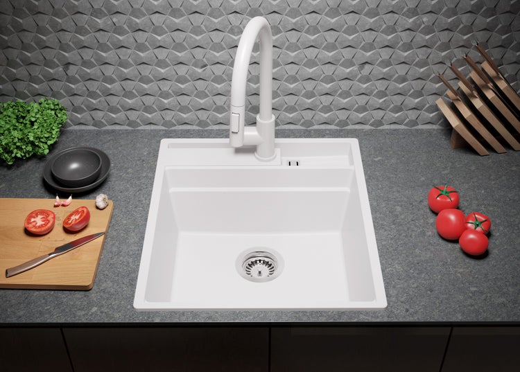 Küchenspüle mit Armatur, umgeben von Tomaten und Küchenutensilien