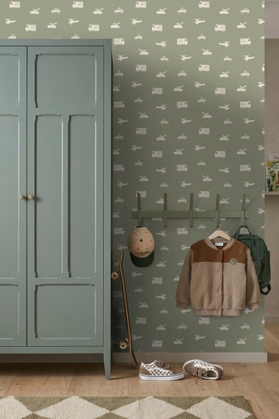 Kinderzimmer mit salbeigrüner Motivtapete mit Fahrzeugen, passendem Kleiderschrank, Garderobe mit Kinderjacke, Skateboard und Turnschuhen.