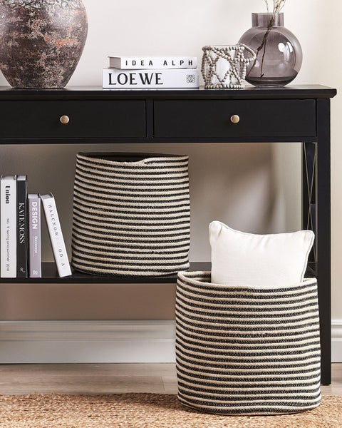 Dekorative Szene mit einer schwarzen Konsole, Körben mit Streifenmuster und Deko-Elementen